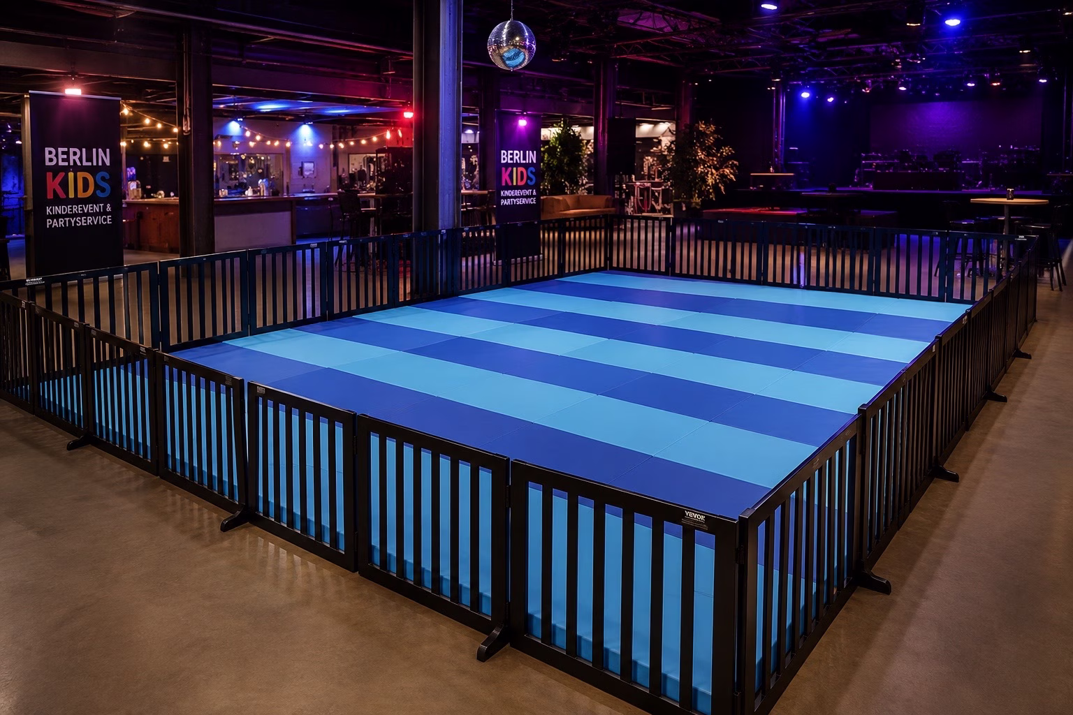 Kinderzone mit blauen Bodenschutzmatten und schwarzen Absperrgittern für Indoor Event in Berlin